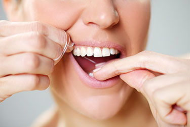 Photo showing correct tooth flossing technique from Main Line Dental Group in Wayne PA
